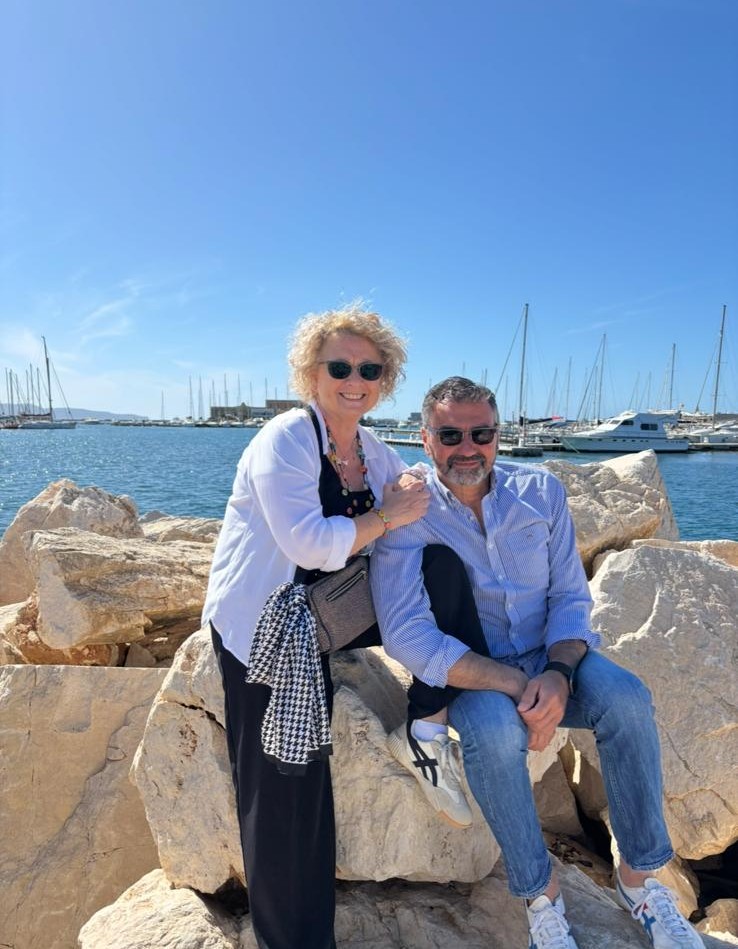 un uomo e una donna seduti su rocce vicino all'acqua